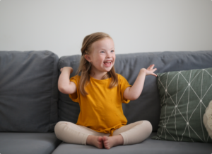a happy smiling child with special needs sitting on a couch