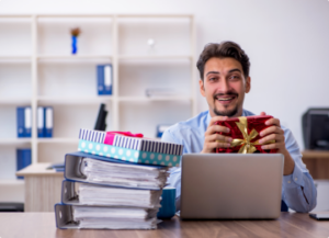 man at his computer holding wrapped gift box