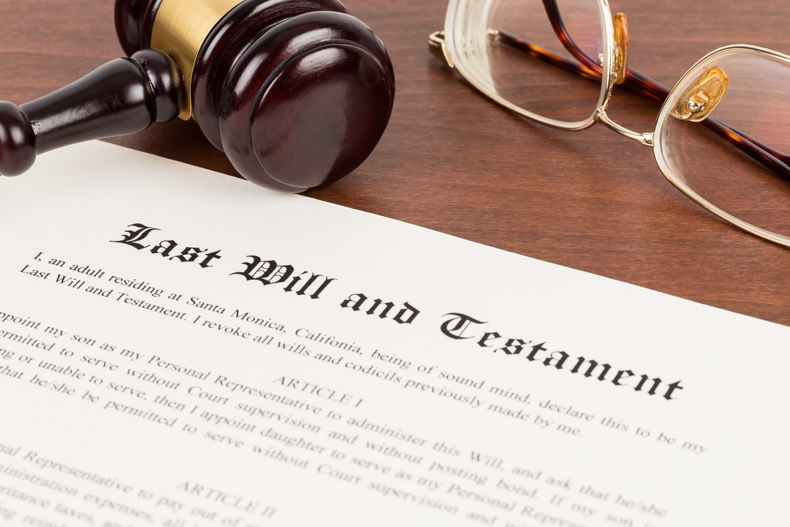 Last will and testament on yellowish paper with wooden judge gavel; document is mock-up